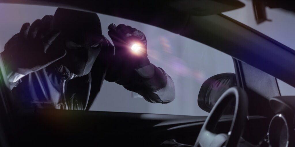 Car Robber with Flashlight Looking Inside the Car