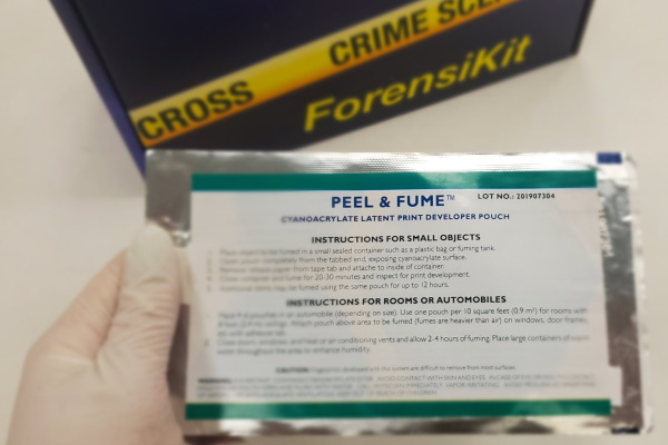 Gloved hand holding a cyanoacrylate fuming pouch with the ForensiKit box in the background